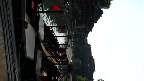 traditional chinese boats docked by the river at sunrise in fenghuang old town, china. vertical