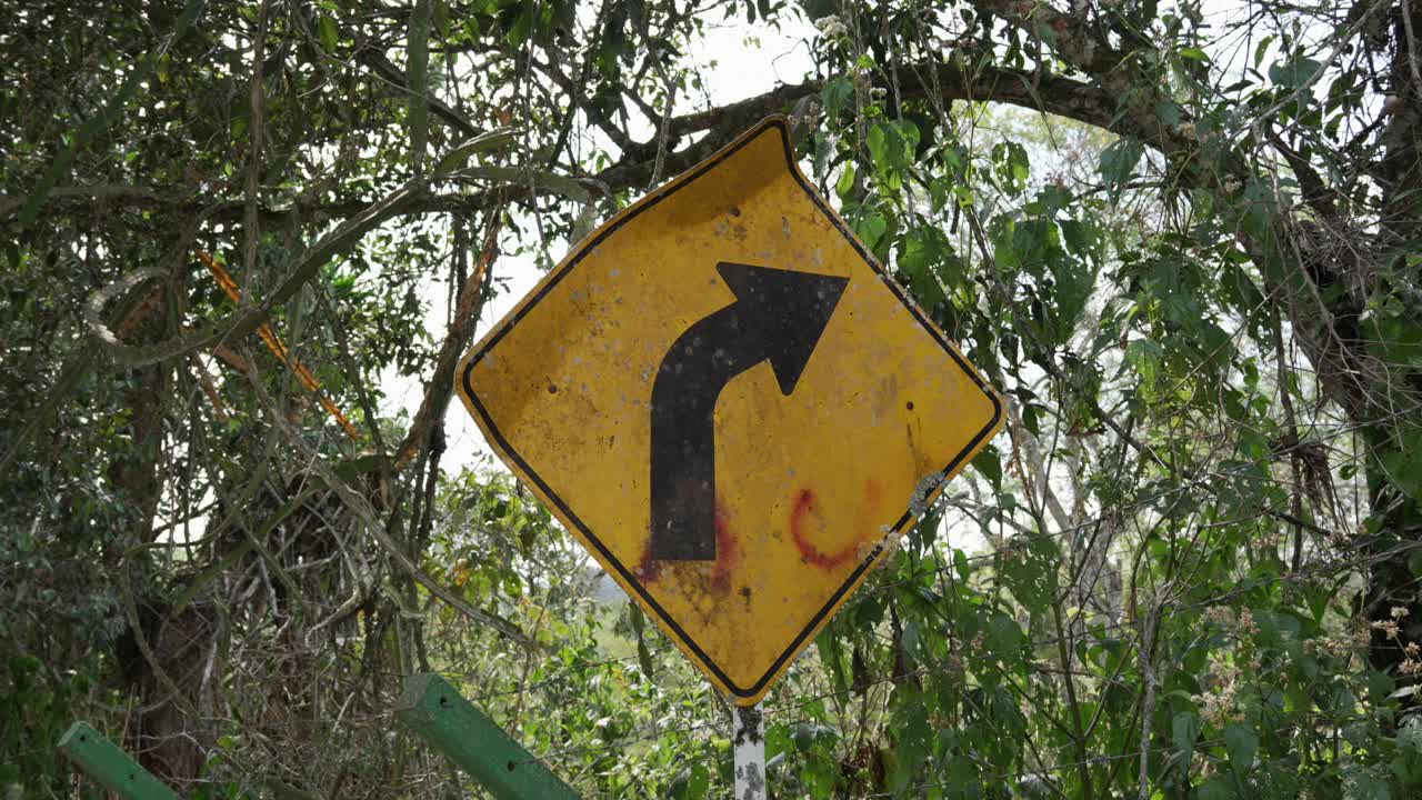Yellow diamond-shaped road sign with a black arrow indicating a sharp right curve turn