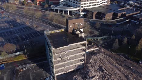 Demolished-multi-storey-car-park-concrete-construction-debris-in-town-regeneration-aerial-rising-tilt-down-over-demolition-site