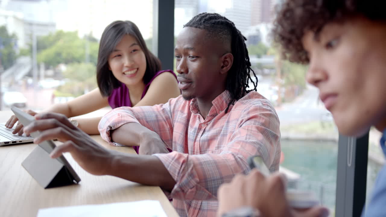 Collaborating in office, diverse team discussing project using tablet and documents