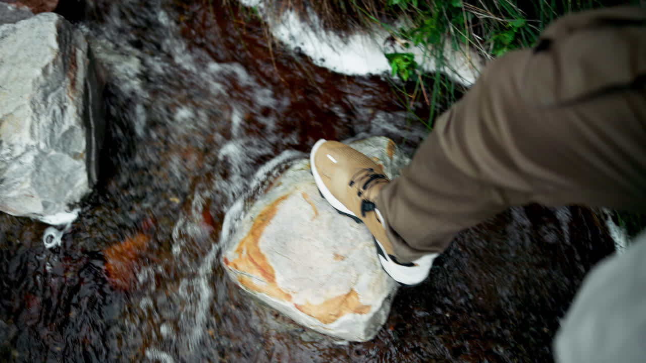 A person standing on rocks next to a stream