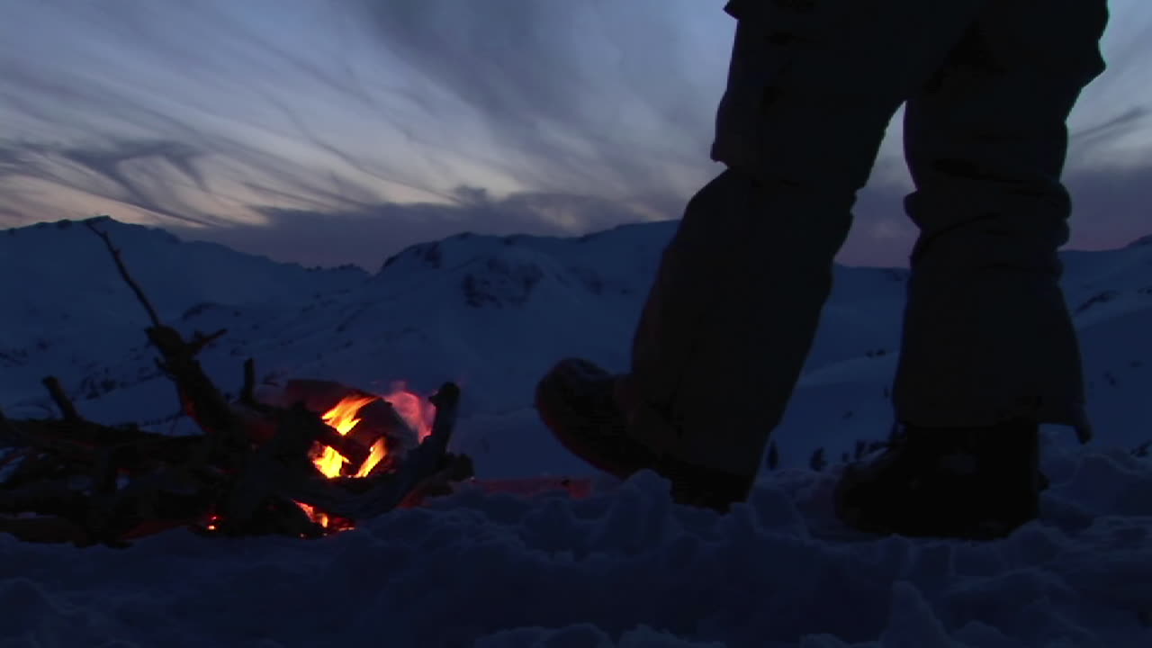 겨울에 모닥불 옆에 있는 남자의 다리를 닫아라