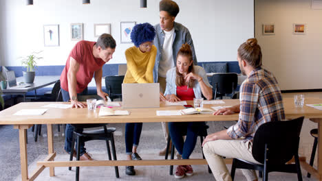 Portrait-of-happy-diverse-business-creatives-using-laptop-in-discussion-in-office,-slow-motion