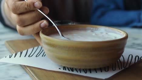 woman eating yogurt dessert at a cafe