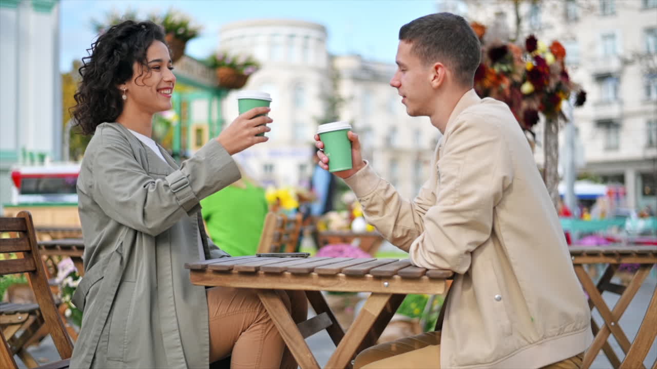 A happy couple outdoors near a cafe. Looking at each other, smiling and talking, coffee. Autumn atmosphere. Slow motion