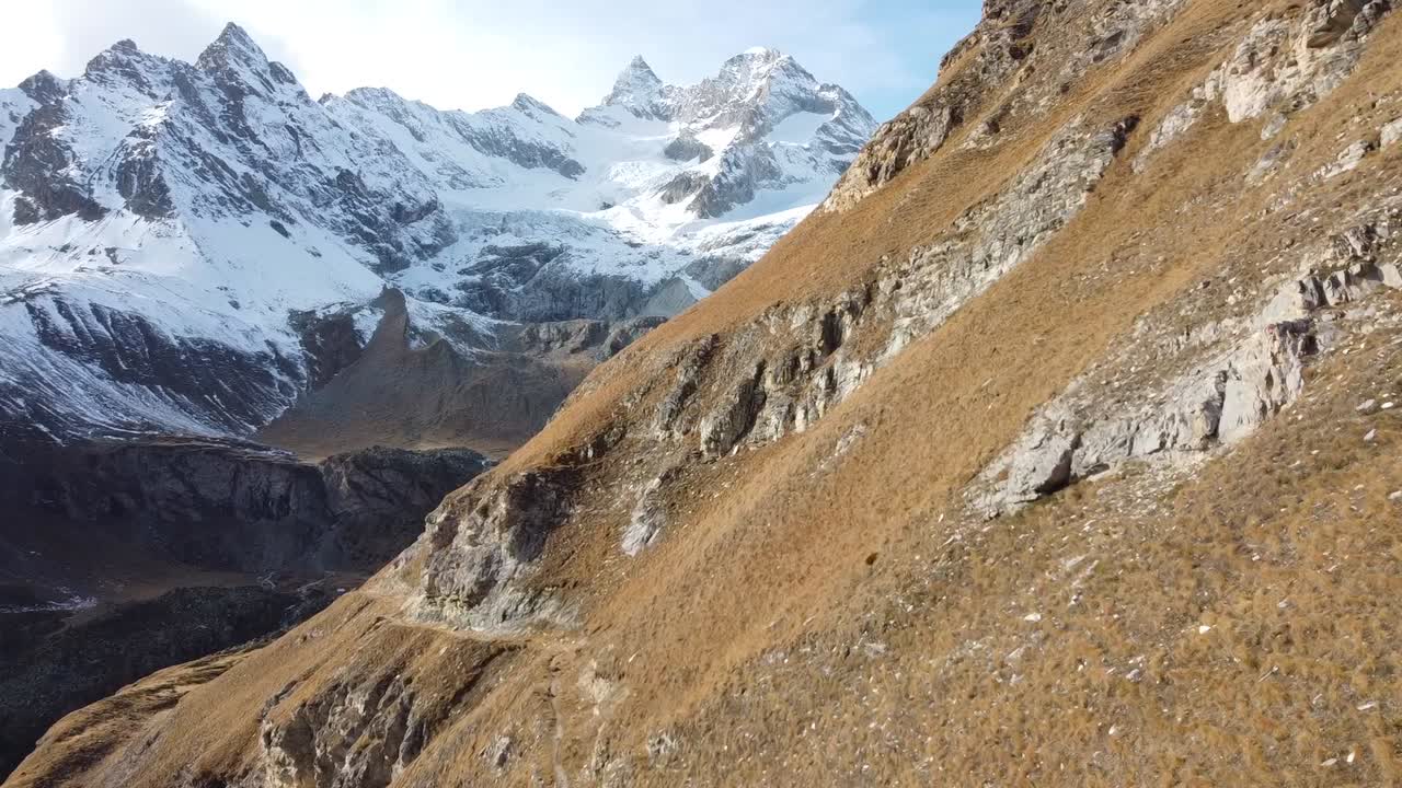cerca del vuelo en prados verdes y escarpados a una cadena montañosa cubierta de nieve en los alpes suizos, un paisaje increíble