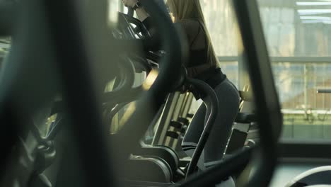 atleta mujer está caminando en orbitrek en el gimnasio. chica está trabajando en stepper para la intensidad de cardio y la mejora de la resistencia