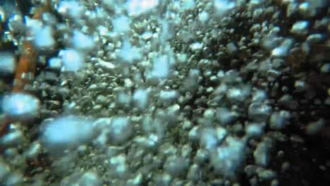 slow motion underwater close up of bubbles from a small waterfall in a forest stream