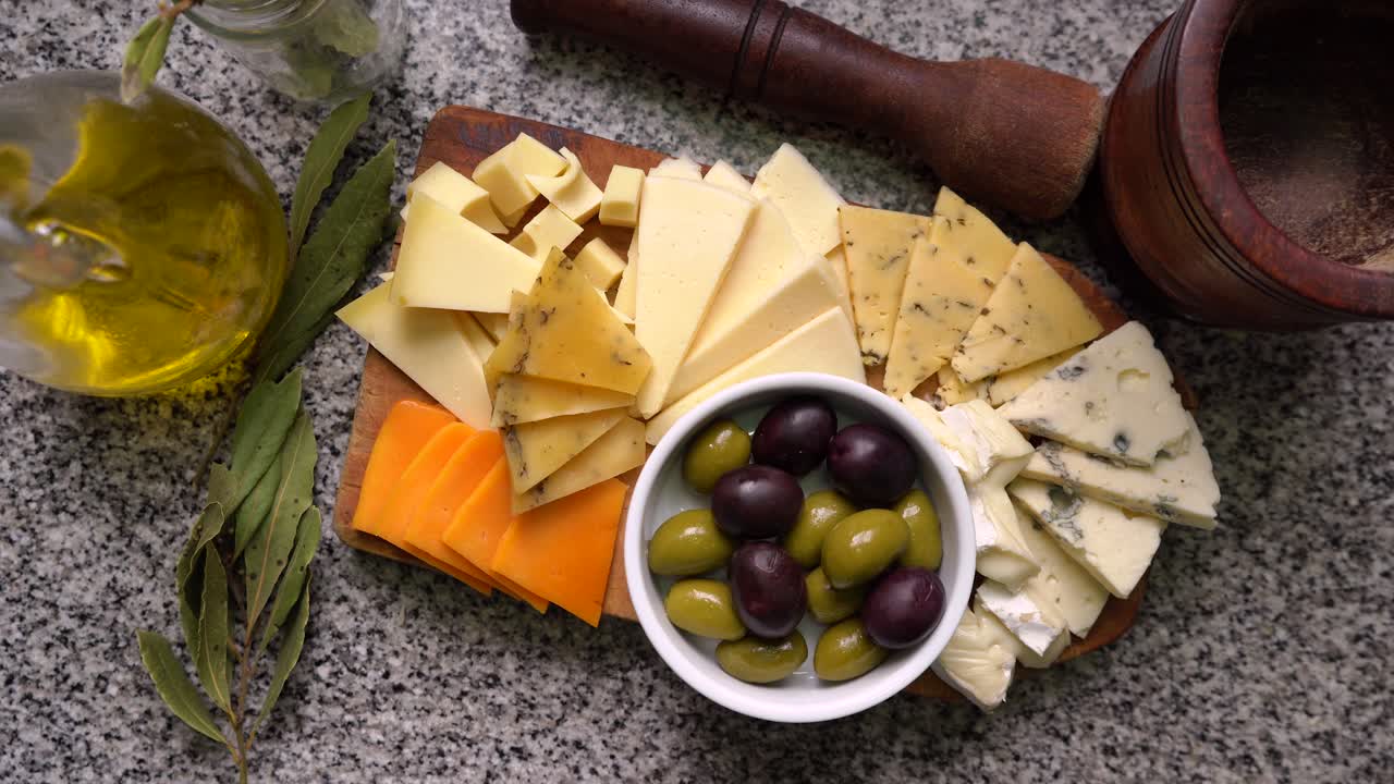 Top view of variety of cheeses with green and black olives. Orbit