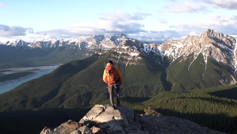 caucasian hiker man arriving at an alpine viewpoint of an epic mountain range epic landscape with snow on the rocky peaks, wide shot, travel concept