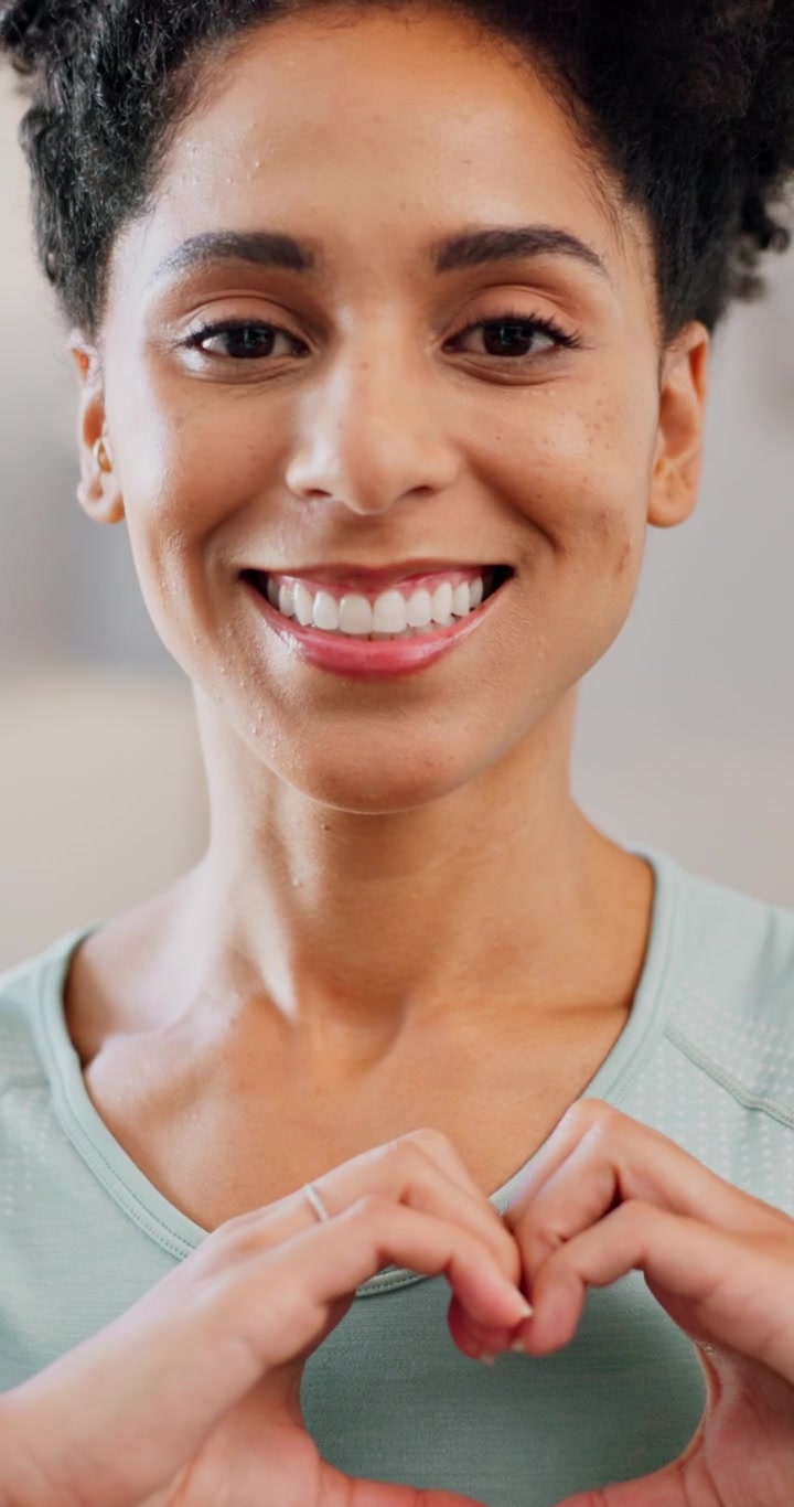 Donna sorridente che fa la forma di un cuore con le mani
