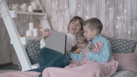 una joven mira una película en una tableta con niños pequeños