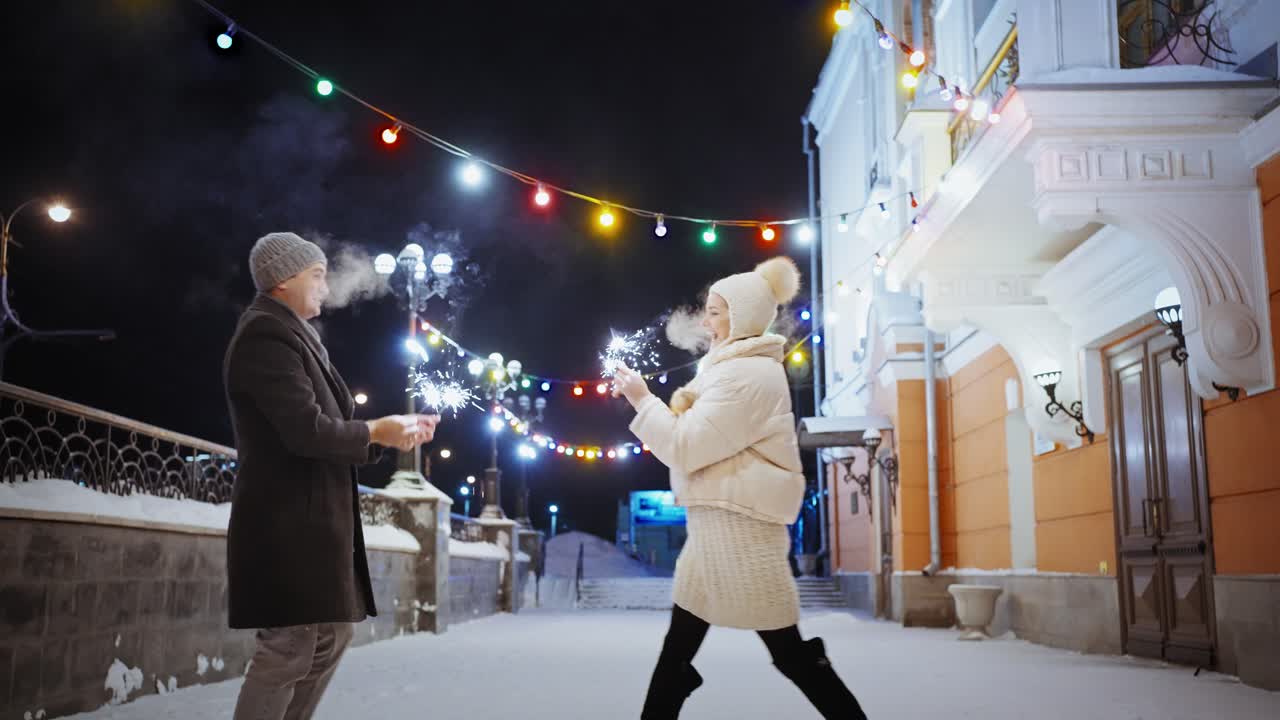 Couple celebrating with sparklers on a snowy night