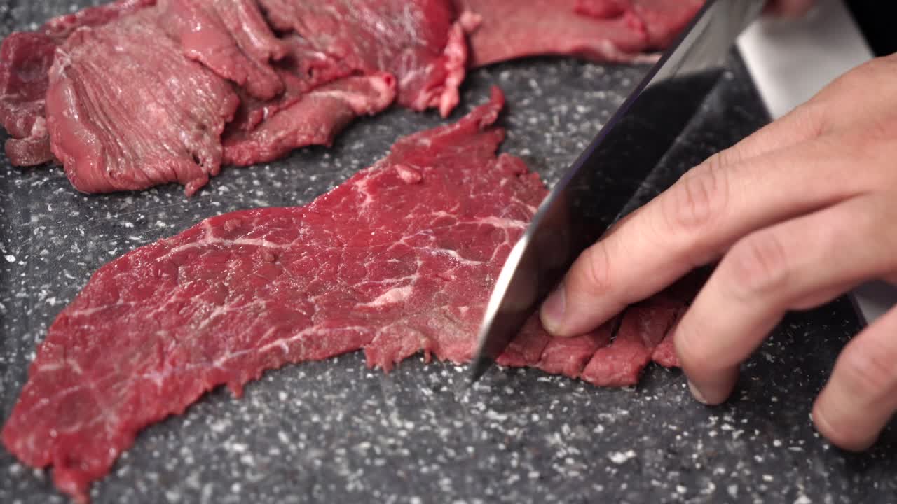 foto macro de un chef cortando carne cruda fresca en una tabla de cortar