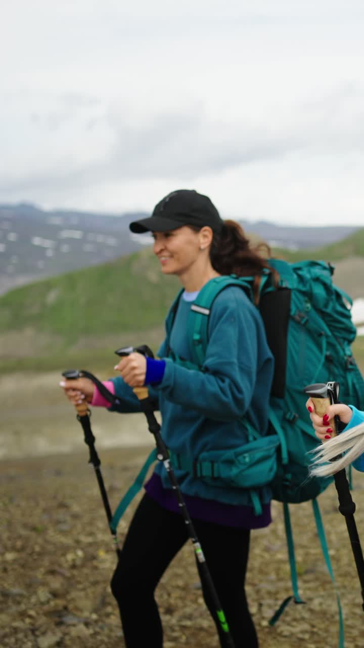 Due giovani donne che fanno escursioni con zaini e bastoncini in montagna