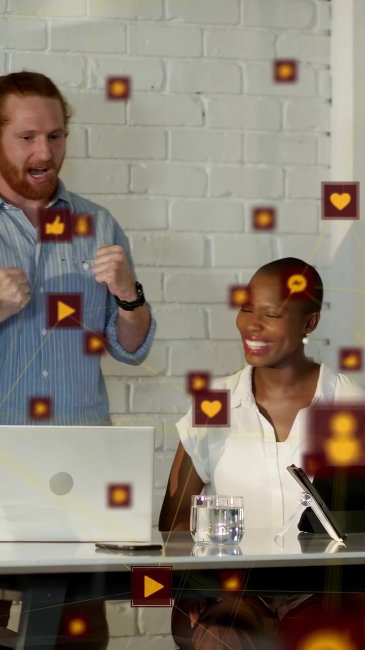 Video verticale: Coppia che si batte il cinque mentre esamina il marketing su laptop o tablet, con icone che fluttuano sullo schermo del dispositivo.