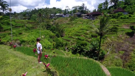 Círculo-De-Drones-Disparó-Alrededor-De-Una-Hermosa-Joven-Parada-Al-Borde-De-Una-Terraza-De-Arroz-En-Ubud-En-Bali,-Indonesia