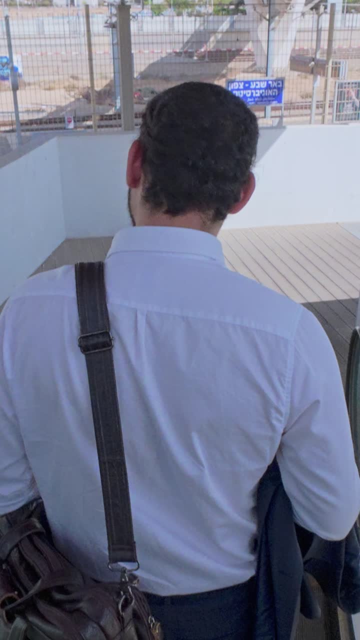 Uomo con camicia bianca che scende le scale, vista da dietro