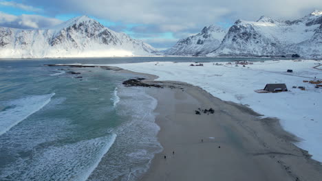 sandy beach in norway covered in snow on a sunny moody day, flakstad beach lofoten, aerial view, forward shot