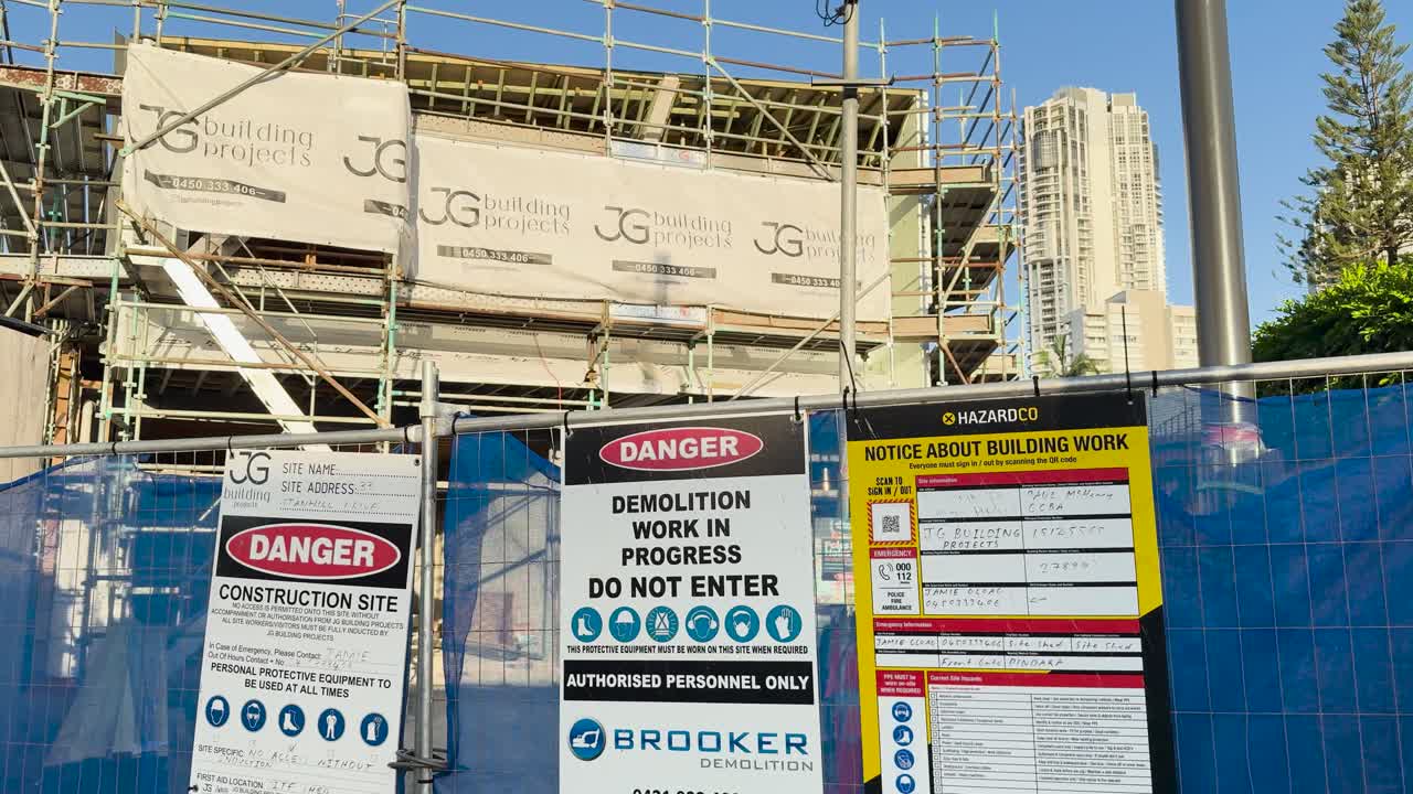 A construction site with safety signs and scaffolding under clear daylight, emphasizing safety protocols and site regulations