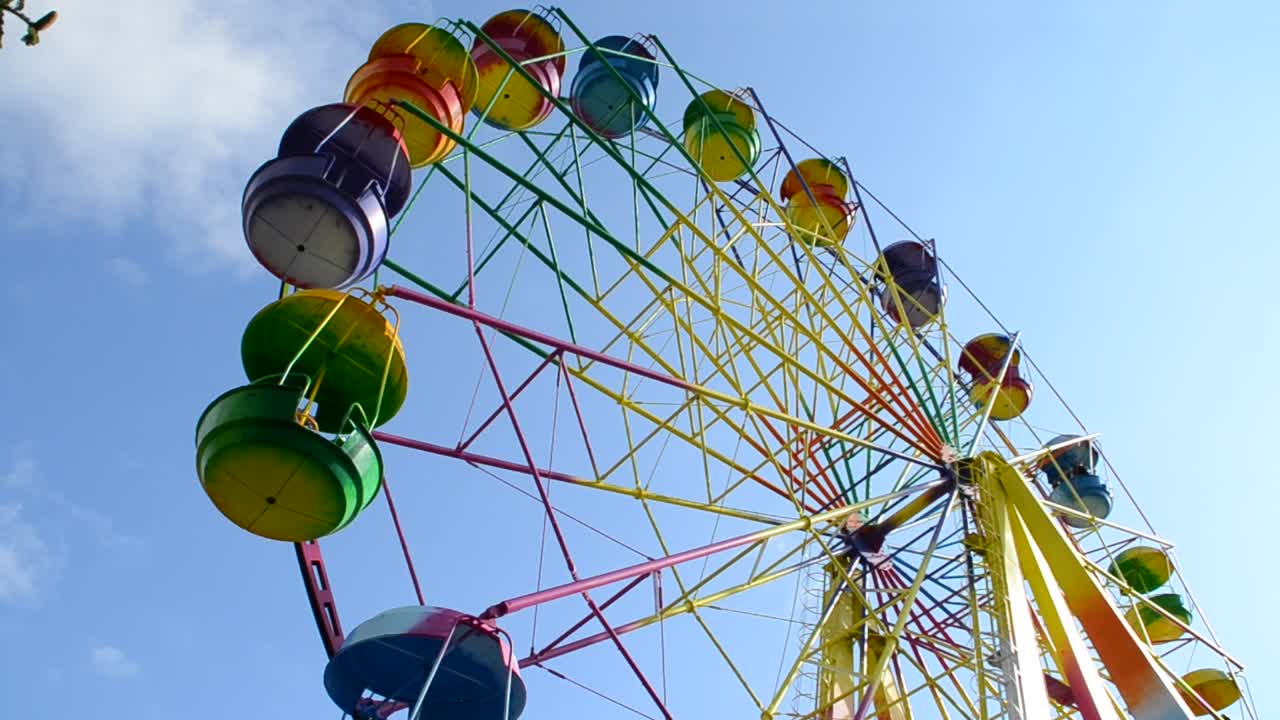 big wheel with multicolored cabins in amusement park