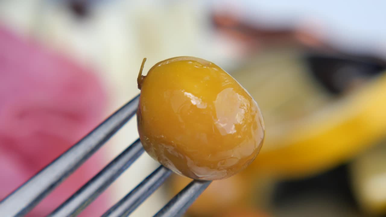 Close-up of a green olive on a fork