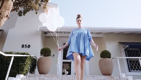 feliz hermosa mujer latina caminando por la ciudad. joven chica rubia disfruta del día en cámara lenta. caminando por la ciudad con globos. 4k. cinematográfico premium