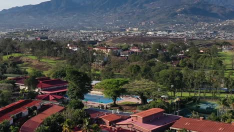 San-Jose-city-valley-in-Costa-Rica-with-golf-course-and-terrace-farms,-Aerial-pan-left-shot