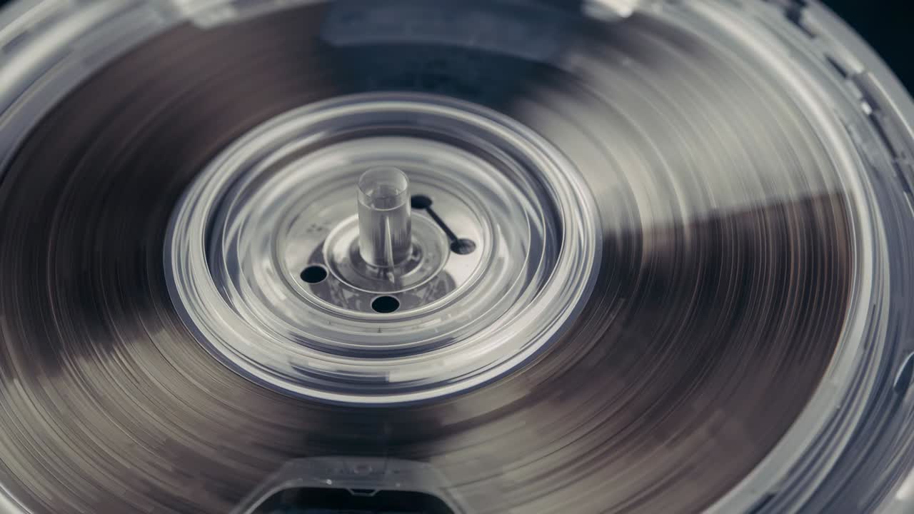 Motor engaging, clear reel hub spinning in cartridge, showing dark tape and rectangular component
