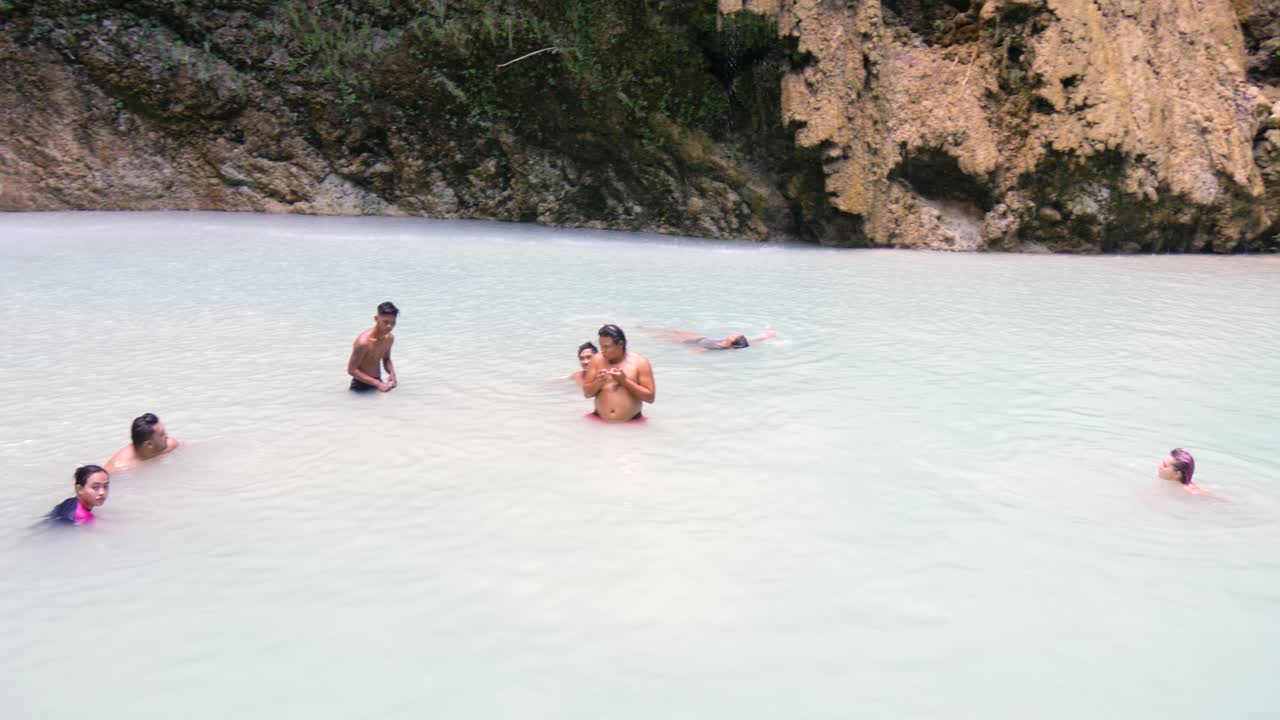 Friends swimming and relaxing in the waters at Tumalog Falls, Cebu, Philippines.