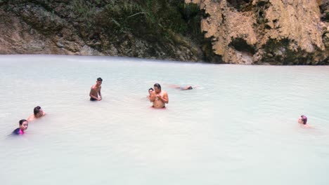 friends swimming and relaxing in the waters at tumalog falls, cebu, philippines.