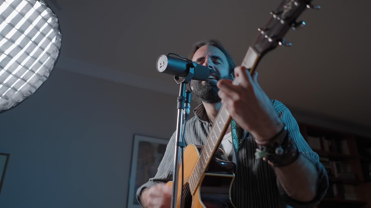 가정 스튜디오에서 어쿠스틱 기타를 연주하는 남자
