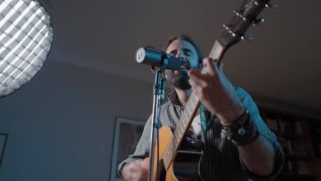 hombre tocando la guitarra acústica en el estudio casero