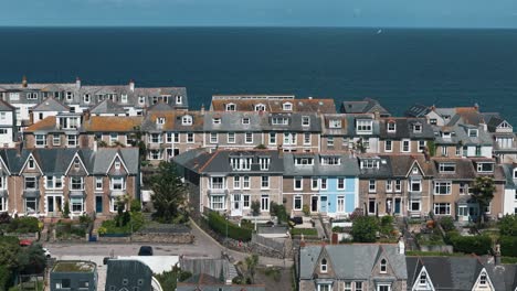 dolly right above hilltop homes in st ives with vibrant ocean and flying seabirds