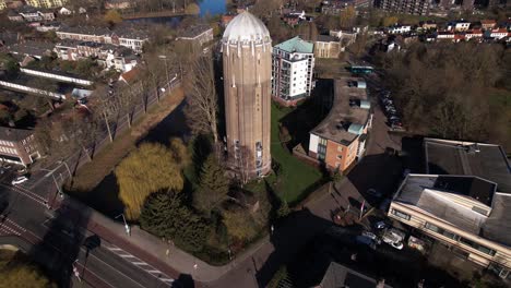 Backwards-aerial-movement-and-reveal-of-former-Dutch-brick-water-supply-tower-in-Zutphen-now-repurposed-as-a-residential-home-in-wider-townscape