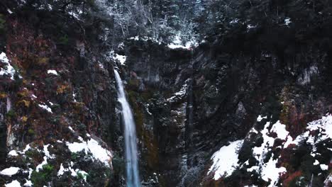 a serene winter wonderland: an aerial perspective of a patagonian mountain forest with a graceful waterfall through the landscape