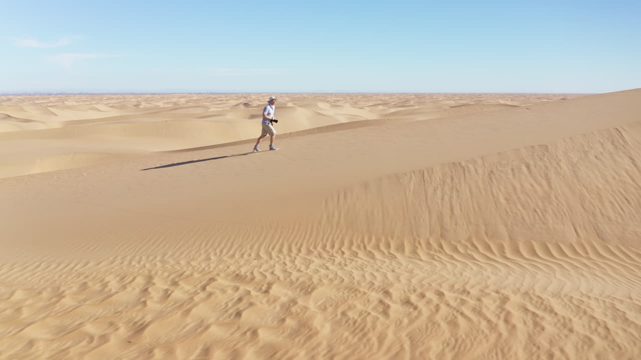 imágenes cinematográficas de un hombre caminando por el desierto con una cámara, tomando una foto del paisaje