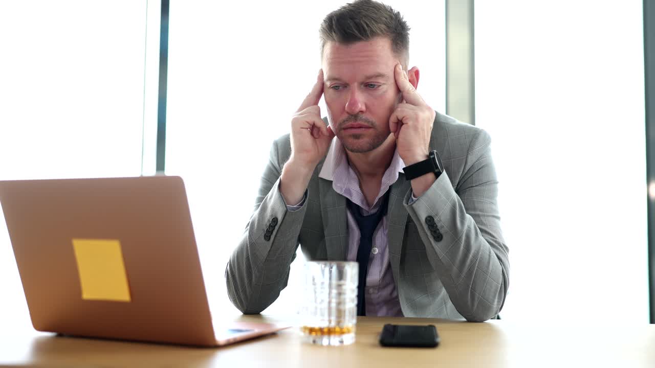 Seo manager with headache and migraine from alcohol addiction is sitting in office