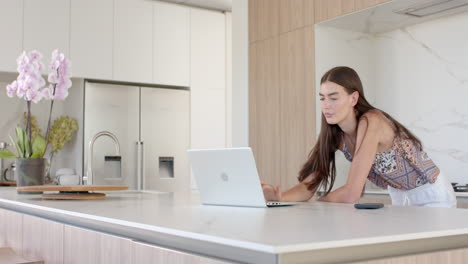 Kaukasisches-Teenager-Mädchen-Konzentriert-Sich-Auf-Ihren-Laptop-In-Einer-Modernen-Küche