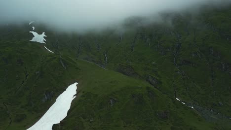 Green-mountains-with-patches-of-snow-under-a-cloud-cover