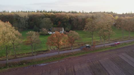 green suv drives on small road with trees during autumn at the netherlands, aerial