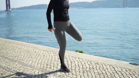 athletic girl in sportswear exercising at riverside