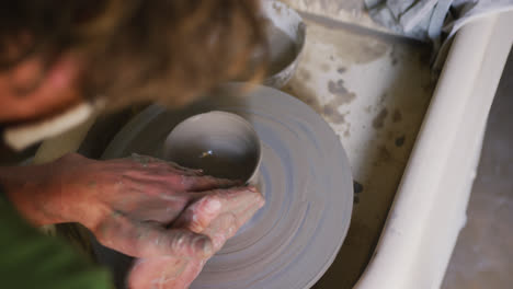 close up view of male potter creating pottery on on potters wheel at pottery studio