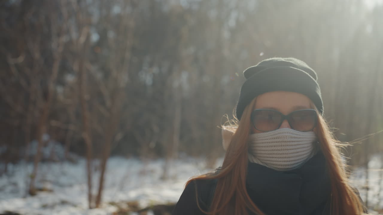 Donna cammina all'aperto. Donna con zaino su sentiero innevato. Donna in silhouette su percorso invernale con cappello. Scena invernale rurale con donna, zaino e berretto che percorre cautamente un sentiero.