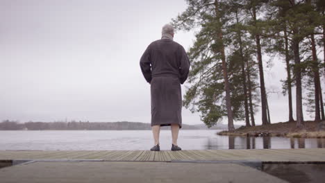 slider shot, a man in his 50s approaches the ice bath spot and removes his robe