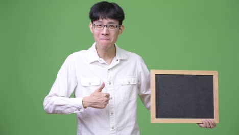 젊은 아시아 사업가 는 엄지손가락 을 올리면서 검은판 을 들고 있다