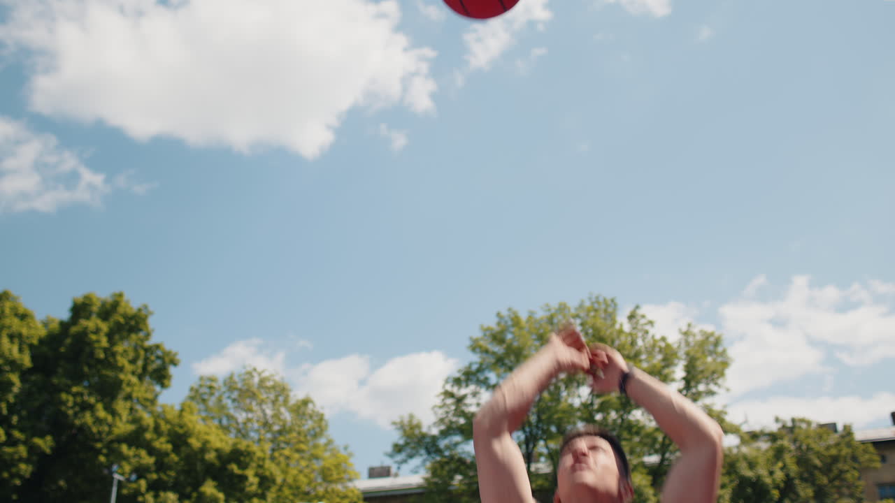 Athletic man in sportswear playing basketball game successfully throws ball into the basket ring
