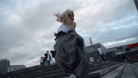 Woman-going-up-stairs-in-urban-background-in-rainy-city-modern-buildings.