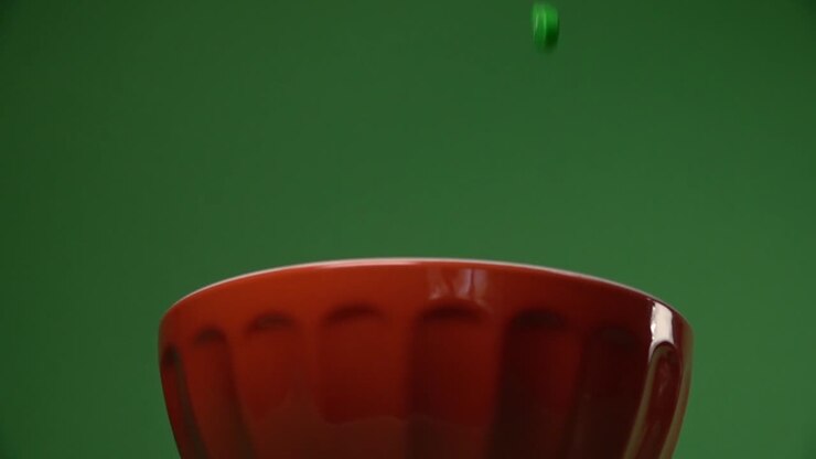 Frontal view of orange and green skulls shaped candy falling on a plate