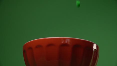 Frontal-view-of-orange-and-green-skulls-shaped-candy-falling-on-a-plate